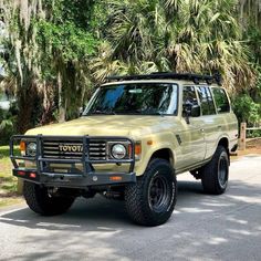 a yellow toyota pickup truck parked in front of some trees