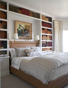 a large bed sitting in front of a book shelf filled with lots of books on top of it