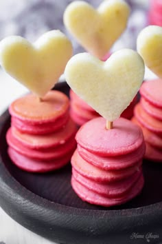 small heart shaped cookies on a plate with candy sticks sticking out of the top one