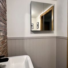 a white sink sitting under a bathroom mirror next to a brick wall in a bathroom