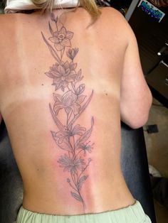 a woman's back tattoo with flowers on her left side and the lower part of her body