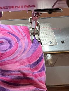 someone is using a sewing machine to sew on something pink and purple swirled fabric