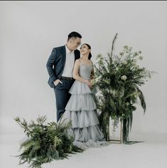 a man and woman standing next to each other in front of some planters with greenery