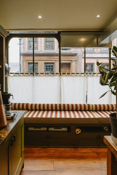 a kitchen with a window seat next to a potted plant