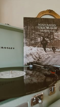 a record player sitting on top of a table next to a box with an album