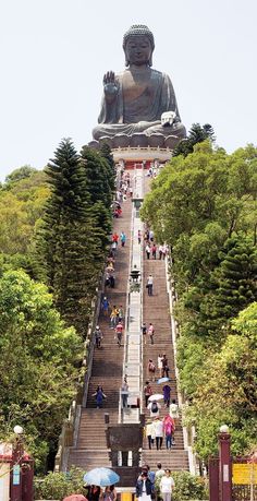 many people are walking up and down the stairs in front of a large buddha statue