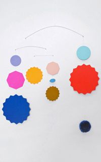 a group of different colored circles hanging from a string on a white wall next to a black object