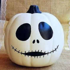 a white pumpkin decorated with black eyes and a jack - o'- lantern face