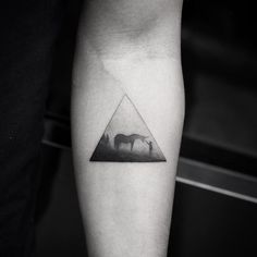 a black and white photo of a horse in a triangle tattoo on the left inner arm