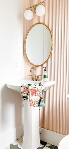 a white pedestal sink sitting under a round mirror