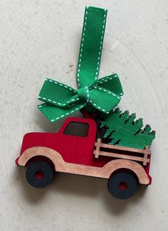 a red truck with a christmas tree tied to it's back on a white surface