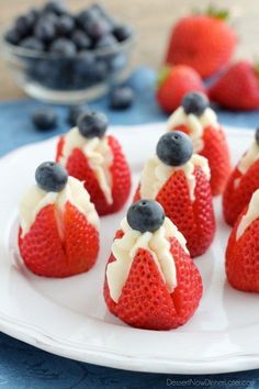 strawberries with cream cheese and blueberries on top are arranged on a white plate