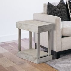 a white couch sitting next to a wooden table on top of a hard wood floor