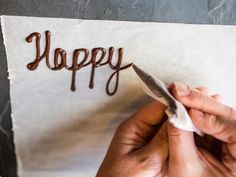 someone is writing the word happy on a piece of paper with a crochet hook