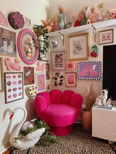 a living room filled with lots of pictures and art on the wall next to a pink chair