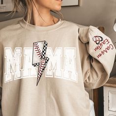 a woman wearing a sweatshirt with the word mmm on it and a lightning bolt in the middle