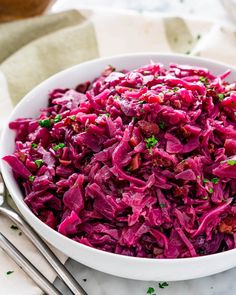 a white bowl filled with red cabbage next to silverware