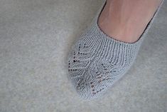 a woman's feet wearing gray knitted slippers