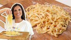 a woman standing next to a pile of pasta on top of a wooden cutting board