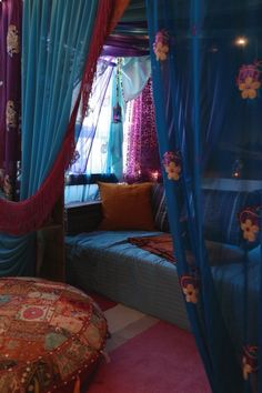 a bedroom with blue curtains, pink carpet and a round ottoman in the middle of the room