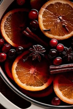 oranges, cinnamon sticks and cranberries are in a pot