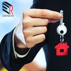 a person holding a house shaped keychain with the word construction written on it