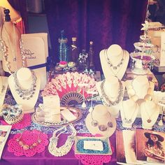 there are many necklaces on display at the table with pictures and other items around it