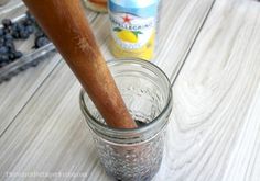 a mason jar filled with blueberries and a wooden spoon sitting on top of it