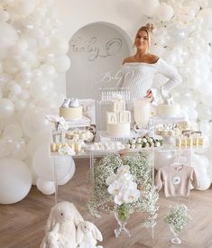 a woman standing in front of a table filled with cakes and desserts at a baby shower