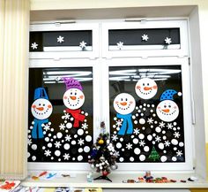 two snowmen are standing in front of the window