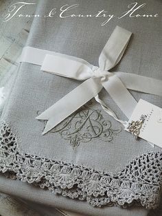 two gray linens with white ribbon and monogrammed initials on them, tied together