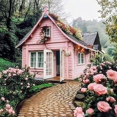 a small pink house in the middle of flowers