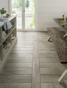 a kitchen with white walls and wooden floors, an open door leading to the outside