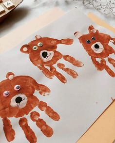 three handprints are shown on a piece of paper with buttons in the shape of bears