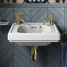 a white sink sitting under a bathroom mirror next to a blue wall with flowers on it