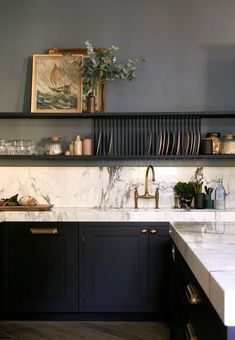 a kitchen with marble counter tops and black cabinets, gold pulls on the cupboards