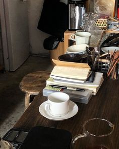 there is a coffee cup and saucer on the counter next to books, magazines, and other items