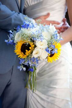 the bride and groom are holding each other's hands with sunflowers in their bouquet