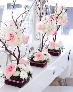 three vases with flowers and branches in them on a table near a window sill