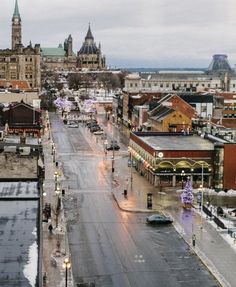 an empty city street in the middle of winter with snow on the ground and buildings