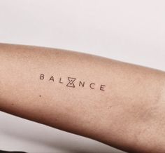 a woman's arm with the word balance tattooed on her left arm, in black ink