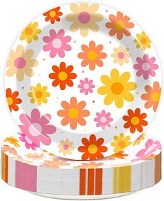 an empty plate with colorful flowers on it next to a stack of paper napkins