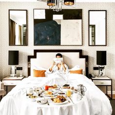 a woman is taking a photo of herself in bed with breakfast on the table next to her