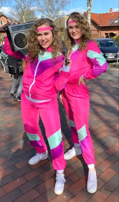 two women dressed in bright pink and green outfits posing for the camera with their arms around each other