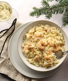 a white bowl filled with shrimp and rice next to a glass of wine