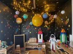 a child's room with space themed wallpaper and wooden desks in front of it