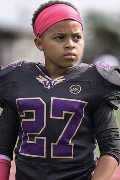 a young man wearing a football uniform with a pink headband