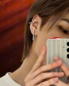 a woman taking a selfie in front of her cell phone with ear piercings