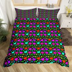 a bed with colorful hearts on it in a room next to a plant and window