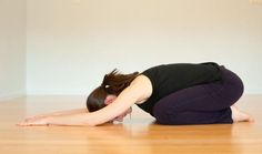 a woman in black shirt doing yoga on wooden floor